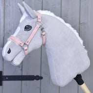 The Hobby Horse LarDen Halter with fur - leatherette Mullbery is a light gray plush hobby horse with a white mane, pink leatherette bridle, and embroidered features mounted on a wooden stick in front of a gray wooden wall.