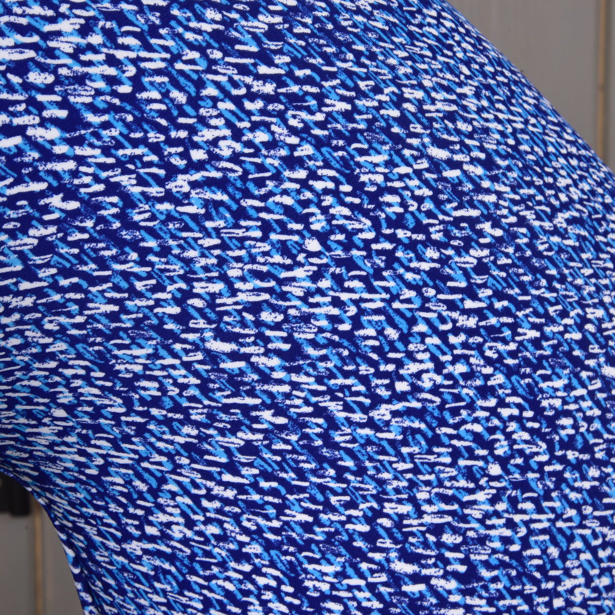 A close-up of the Hobby Horse LarDen "See" protective suit’s PES fabric, showing a blue and white abstract pattern of small, irregular dashes and spots for a dynamic, pixelated look.