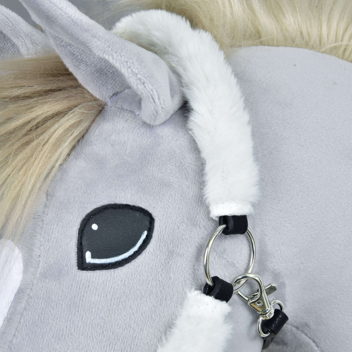 Close-up of the Fur Halter Teddy Classic by Hobby Horse LarDen: plush gray toy horse’s face with a stitched black and white eye, furry white mane, soft ear, and a halter with a silver ring and clasp.
