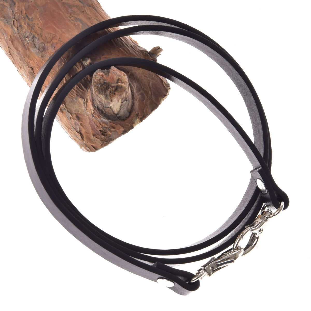 The Reins Black leatherette by Hobby Horse LarDen, featuring a metal clasp, is wrapped around a tree branch and displayed on a white background—highlighting craftsmanship reminiscent of premium reins.