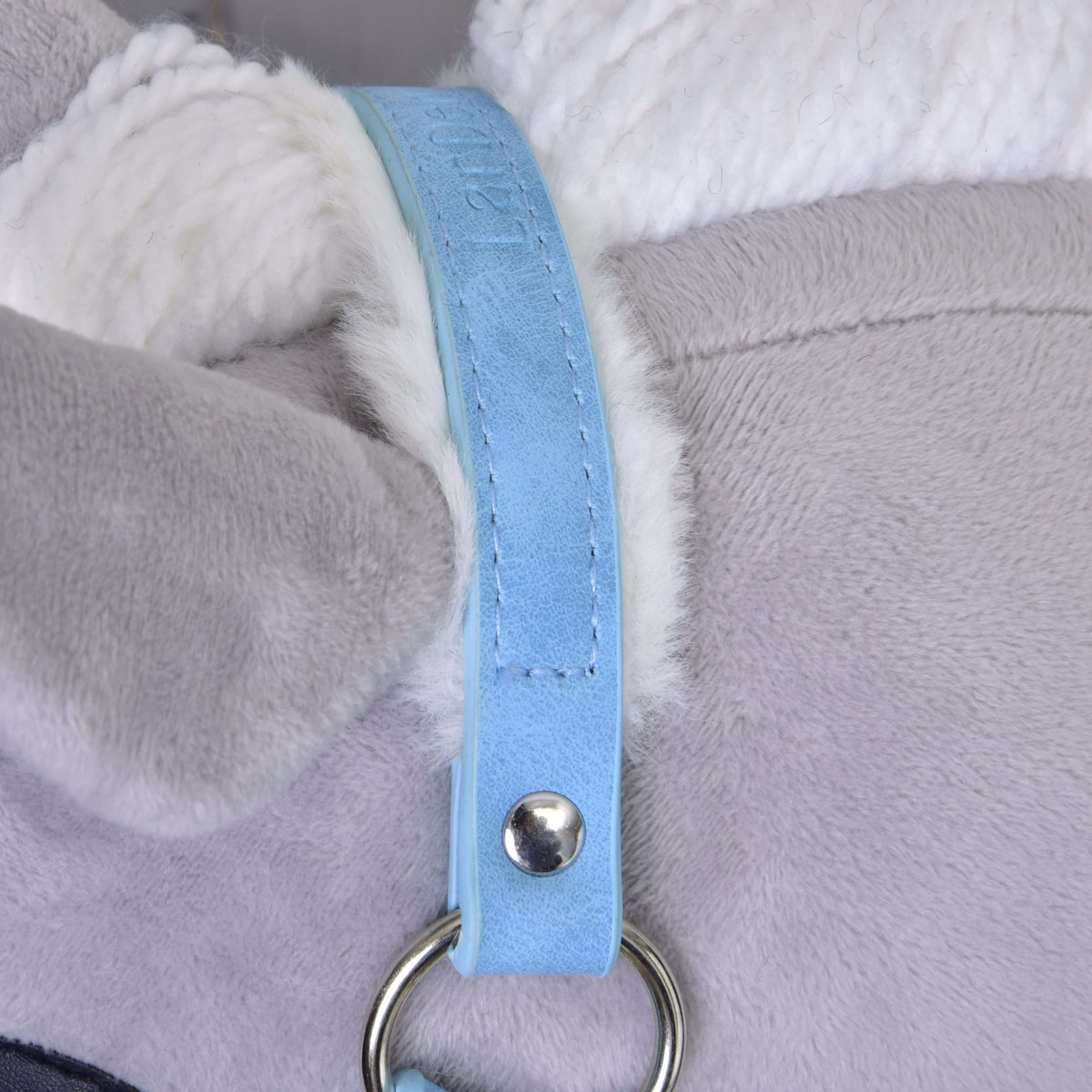 Close-up of the Hobby Horse LarDen Halter with fur - leatherette Pastell Blue, featuring light gray plush, white accents, and a pastel blue strap attached by a silver ring and rivet.