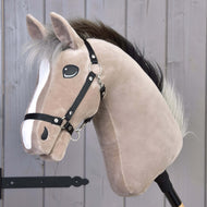 The Hobby Horse LarDen Piccolino features a light brown plush Holsteiner sport horse with a white facial stripe, black halter, fluffy mane, and is mounted on a wooden stick, shown in front of a gray wooden wall.