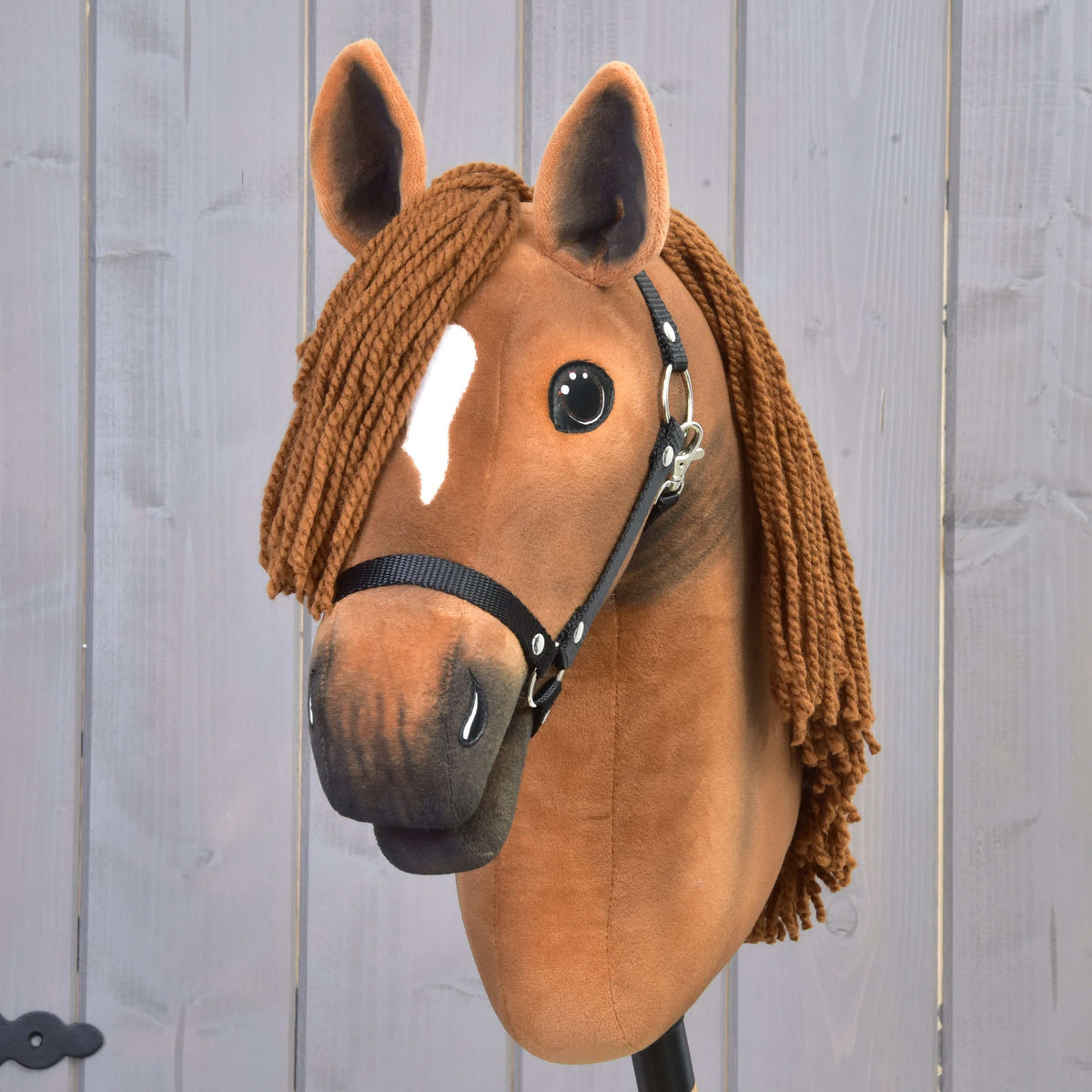 Front view of Hobby Horse Pippa with a small white stripe, brown yarn forelock and black halter