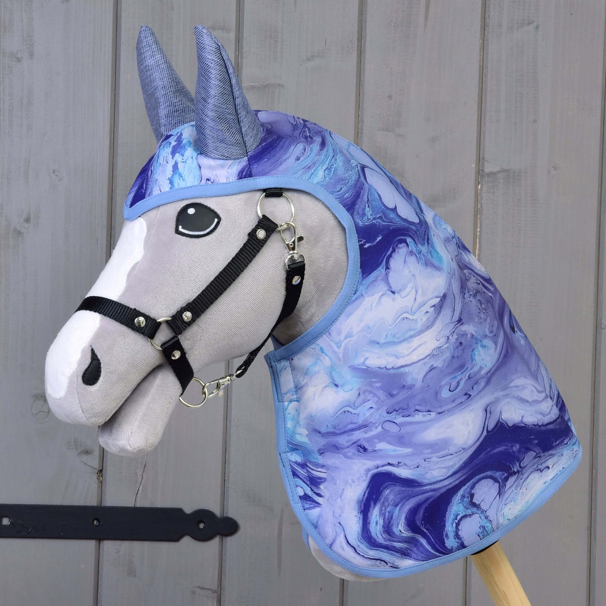 Grey Hobby Horse in a black halter wearing the Raincoat Galaxy Blue with marbled blue and purple print and blue-grey ears