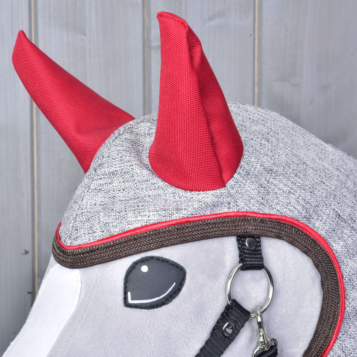 Close-up of the red ear covers and the brown binding with red piping around the face opening of the grey raincoat