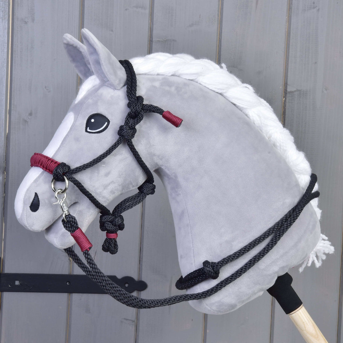 The Rope set Maroon by Hobby Horse LarDen is shown in front of a gray wooden wall, featuring maroon-colored ropes designed for hobby horses.