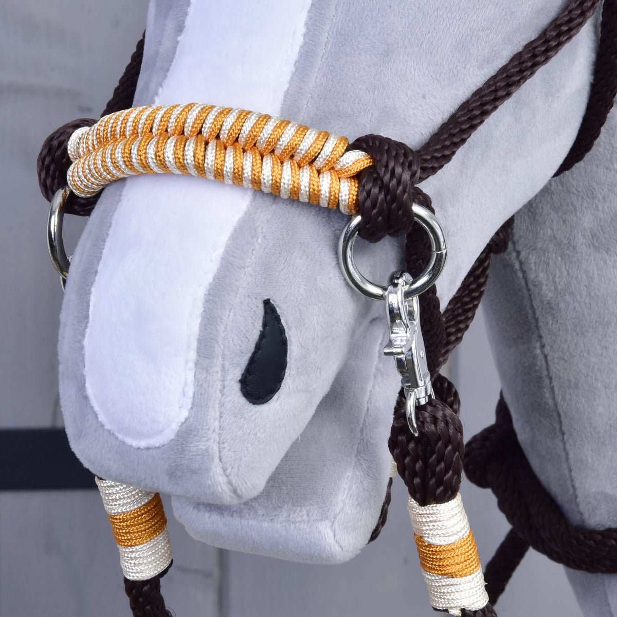 Close-up of a Hobby Horse LarDen head with the Rope set Orange bridle, silver hardware, and matching orange reins. The plush toy has a gray face, white nose stripe, and black oval nostril.