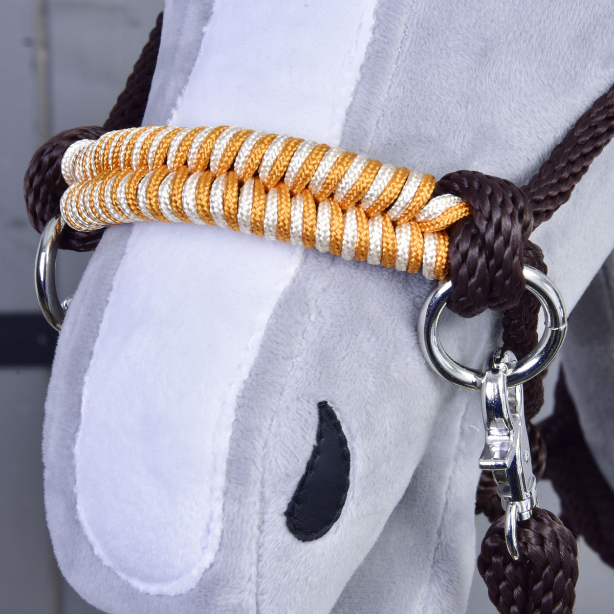 Close-up of a Hobby Horse LarDen plush face, showing a white snout, black nostril, and a gold and white halter with shiny metal rings plus matching brown reins from the Rope set Orange.