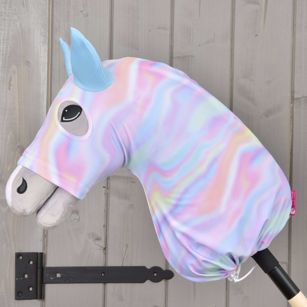Side view of a grey Hobby Horse in the Protective suit Rainbow, pastel swirl Lycra gathered with a drawstring at the stick