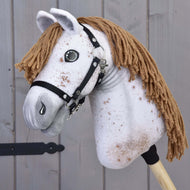 The Hobby Horse LarDen "Hobby Horse Rufus with Black Halter" features a handmade, speckled white fabric head, brown yarn mane, button eyes, and black halter on a wooden stick, shown against a gray wood background.