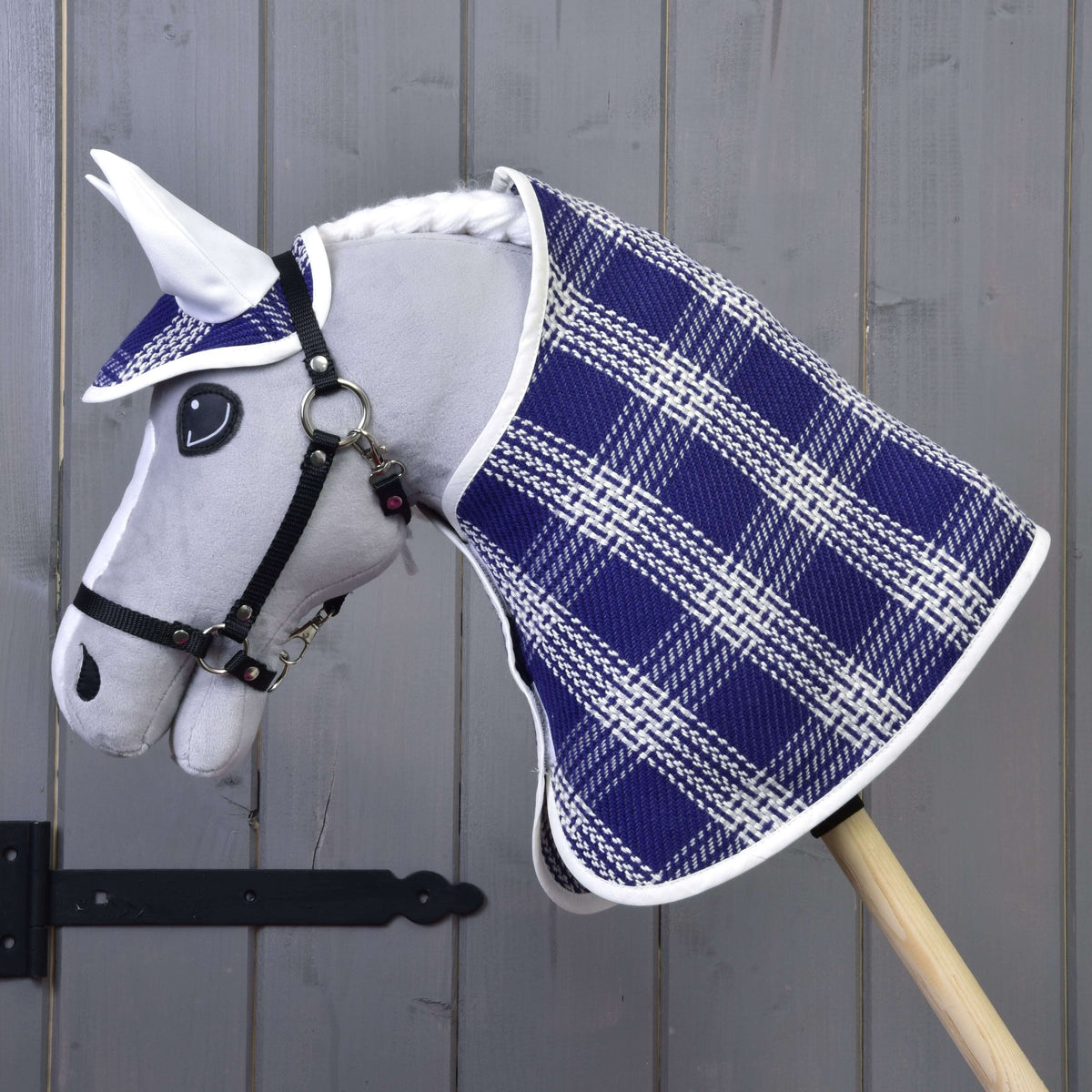 The Hobby Horse LarDen "Set Blue Cube" features a gray plush head, blue and white checkered blanket set with matching ear bonnet, mounted on a wooden stick before a gray wooden wall.