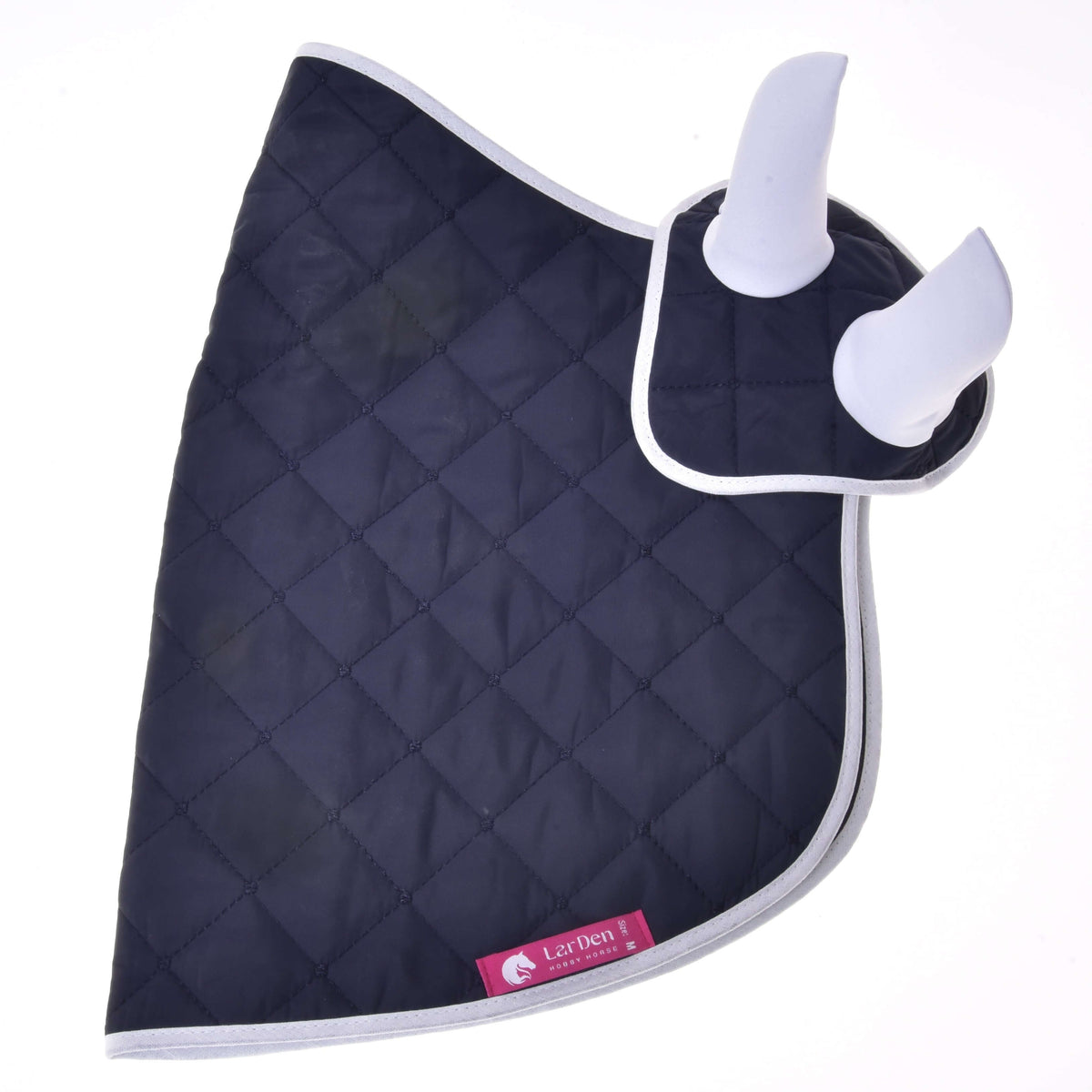 The Set Monte by Hobby Horse LarDen is a navy blue quilted blanket with light gray trim and two white padded ear covers, forming a stylish ear bonnet set. A pink label with the horse logo adds extra decoration to your horse’s look.