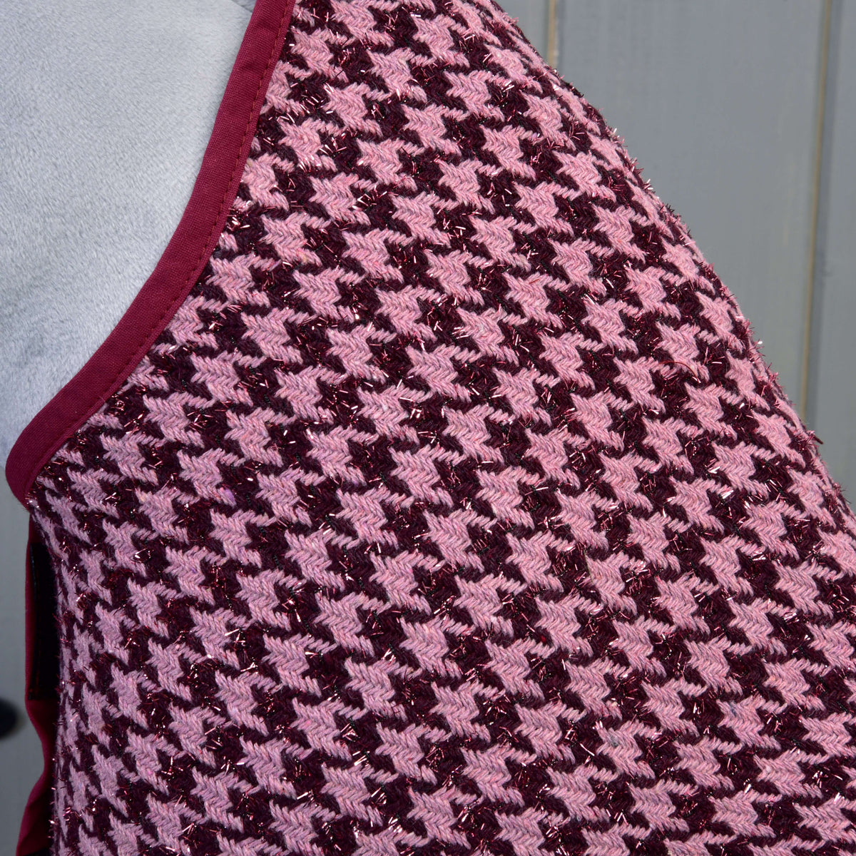 Close-up of the Set festive Bordeaux by Hobby Horse LarDen, featuring a pink and maroon houndstooth pattern with dark red trim, echoing a chic blanket design, set against a grey background.