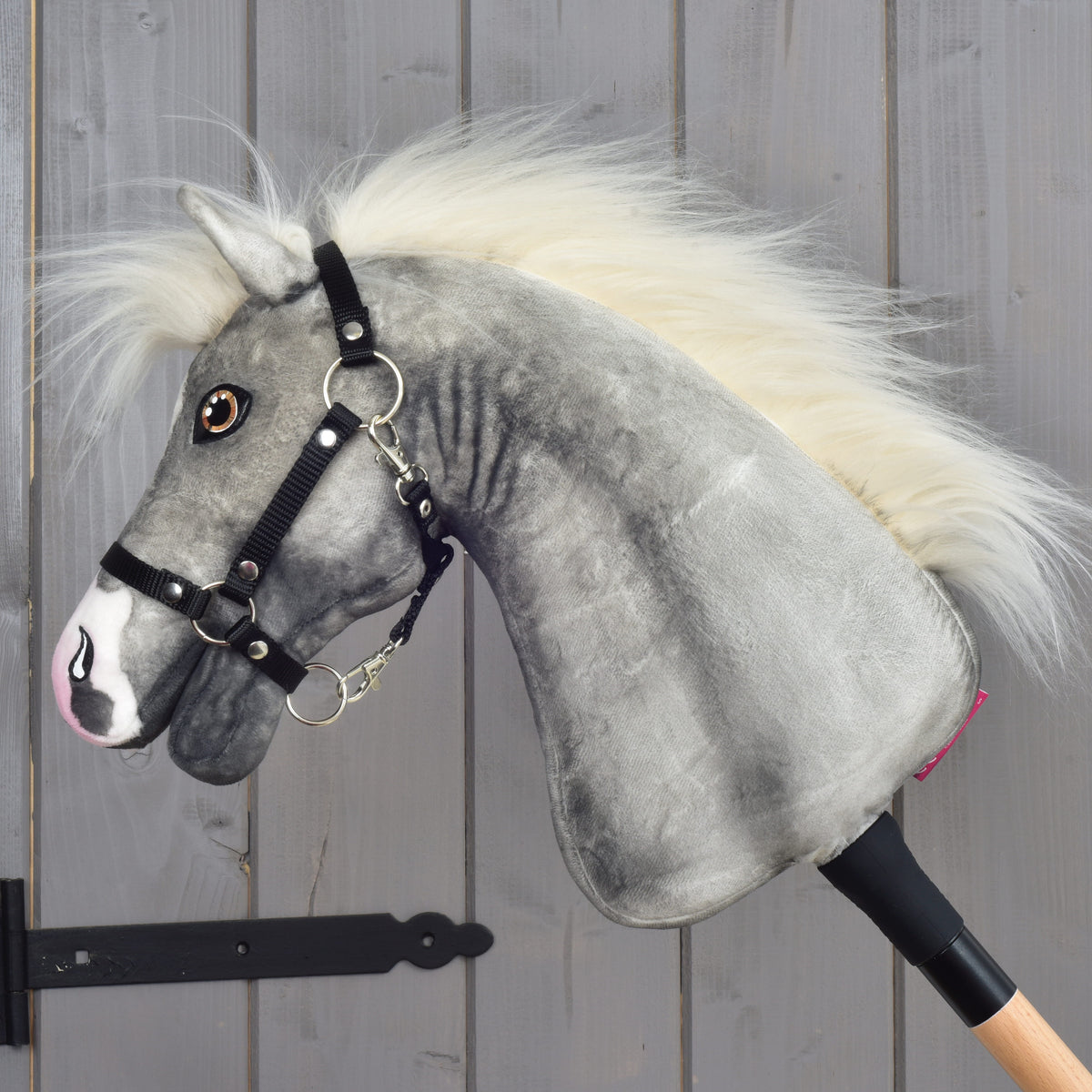 Hobby Horse Silver Moon in left profile with amber eyes, a long flowing cream mane and a black halter on a wooden stick