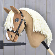 The Hobby Horse LarDen "Hobby Horse Smart with Black Halter" features a plush tan face, white yarn mane, and black halter on a wooden stick, displayed against a gray wooden wall.