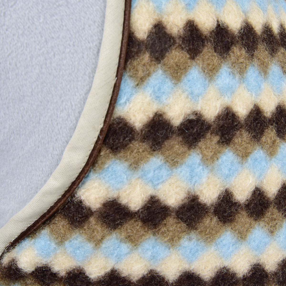 Detalje af fleecen med ruder i brun, gråbrun, creme og lyseblå samt det beige kantbånd på Hobby Horse stalddækken Pastel Argyle