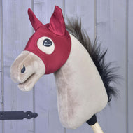 The Hobby Horse LarDen "Horse Mask Barn Red" features a light brown face, black mane, and red barn bridle, mounted on a stick and set before gray wooden planks.