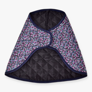 The Blanket Flower by Hobby Horse LarDen is a quilted, cape-style garment with black lining, a dark floral pattern of small blue and purple flowers, and dark blue trim—evoking a cozy horse blanket.