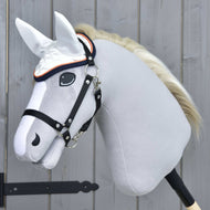 The Hobby Horse LarDen Ear Bonnet Speedy is a realistic gray hobby horse with a black bridle, white mane, and white fly-protective ear bonnet, mounted on a wooden stick in front of a light gray wooden wall.