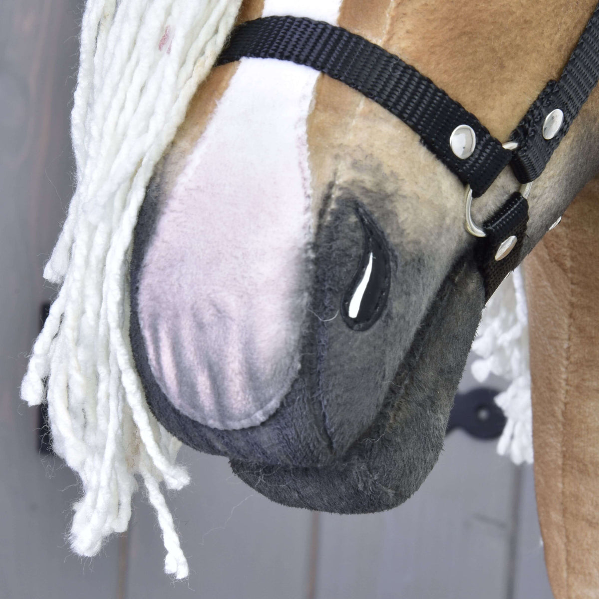 Close-up of Hobby Horse LarDen’s handmade Connie, featuring a light brown and white face, black halter, and white yarn mane. Detailed stitching and fabric texture are visible.