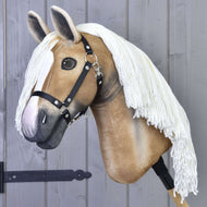 The Hobby Horse LarDen “Connie with Black Halter” features a realistic tan and white design, a long white yarn mane, and is shown mounted on a stick against a gray wooden wall.