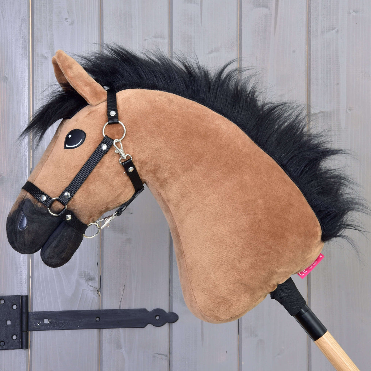Den lysebrune Hobby Horse set fra siden med luftig sort manke, sort mule og sort grime på en kæp