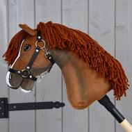 Hobby Horse LarDen’s Hobby Horse Cooper with Black Halter features a brown fabric head with a yarn mane, a white blaze on its nose, and comes mounted on a wooden stick. Styled to resemble an elegant sport horse, it’s perfect for imaginative dressage adventures and is photographed here against a gray wooden background.