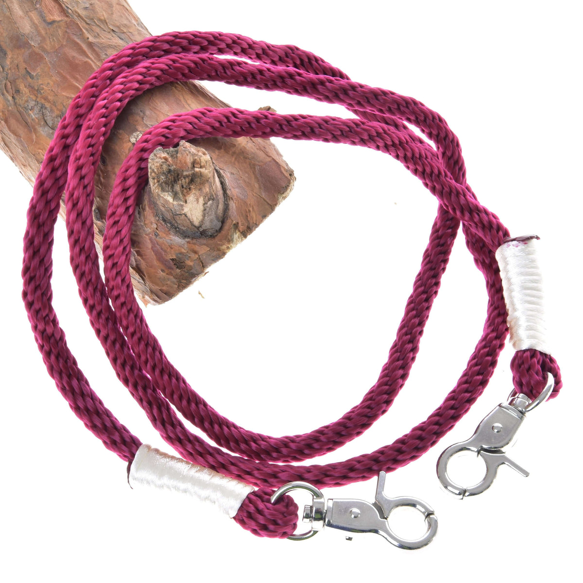 The Reins Czi-czi by Hobby Horse LarDen is a braided dark pink polypropylene rope lanyard with silver lobster clasps and white thread wraps at each end, coiled on wood—ideal as stylish handmade reins or for hobby horse play.