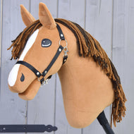 Hobby Horse LarDen's chestnut stallion, Hobby Horse Edward with Black Halter, features a white blaze and brown yarn mane, standing on a stick before a gray wooden wall.