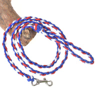 The Hobby Horse LarDen "Hobby Horse - rope stripe Flag CZ" leash, in blue, red, and white with a metal clip and looped handle, is coiled on wood—ideal for guiding your pet or as a hobby horse leash.