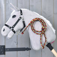 The Hobby Horse LarDen "Hobby Horse - rope stripe Flag" is a gray plush hobby horse with a stick body, white mane, black bridle, and a braided red, yellow, and black leash, shown against a wooden background.