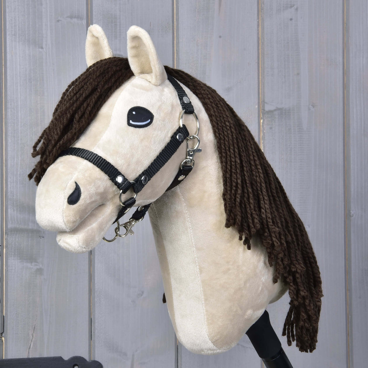 The Hobby Horse LarDen Frederik LD features a beige face, black halter, and long brown yarn mane, shown against a light gray wooden background.