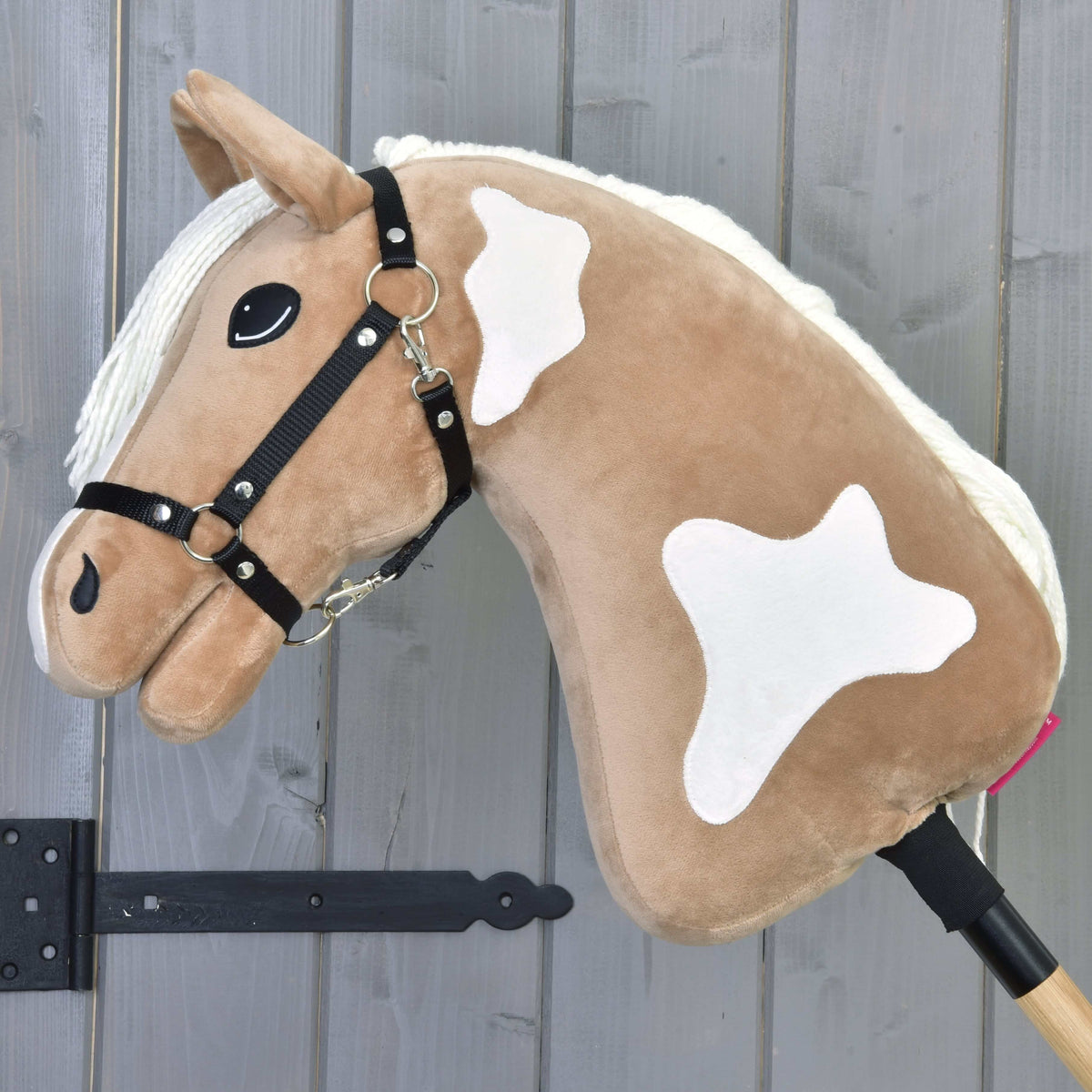 The Hobby Horse Fury with Black Halter by Hobby Horse LarDen features a light brown body, white mane, and spots on a wooden stick. It includes a black halter and stitched eye—perfect for imaginative trail rides.