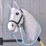 The Reins Heaven by Hobby Horse LarDen is a plush gray hobby horse with a white muzzle, black bridle, and blue polypropylene rope reins, mounted on a wooden stick and shown against wood paneling.