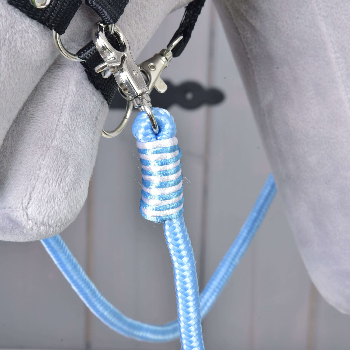 Close-up of blue and white polypropylene rope from Reins Heaven by Hobby Horse LarDen, tied and clipped to gray fabric—ideal for use as hobby horse or handmade reins.