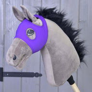 A plush hobby horse with a black mane, gray face, and a Hobby Horse LarDen Horse Mask without ears in indigo, made from washable PES material, mounted on a wooden stick and set against a gray wooden wall.