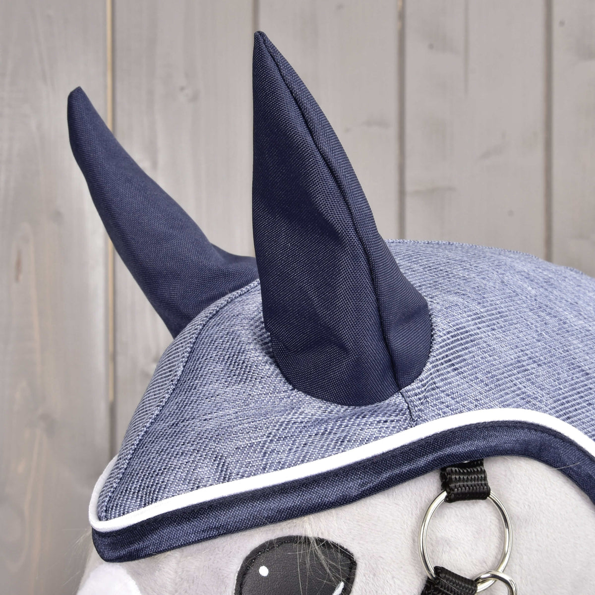 Nærbillede af hætten på regndækkenet Jeans med mørkeblå ører og denimblå top med mørkeblå og hvid kant