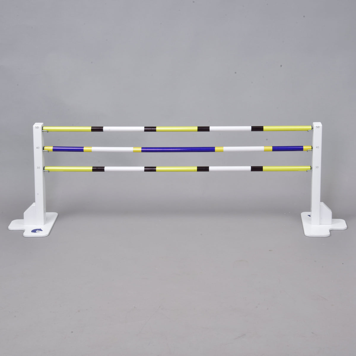 A white horse jumps the Hobby Horse LarDen Jump 50 cm / 20 inch with extra yellow, white, blue, and black poles against a gray background. Ideal for indoor or outdoor Hobby Horsing activities.