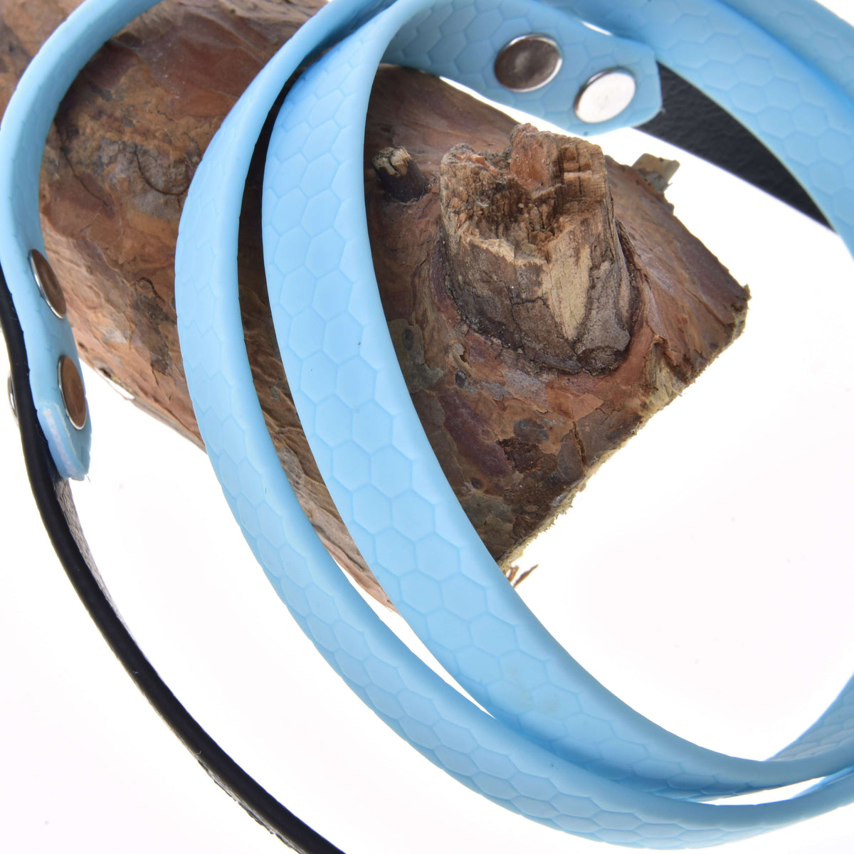 A close-up of Hobby Horse LarDen Reins rubberized Light blue with metal snaps, draped over brown wood against a white background.