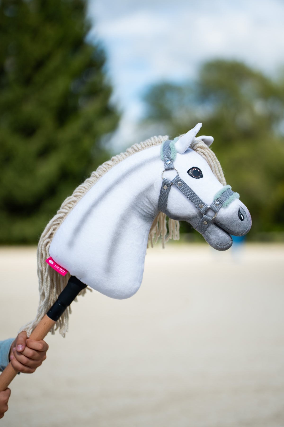 Hobby Horse Little Lady with Black Halter shown outdoors with a white plush head and cream yarn mane