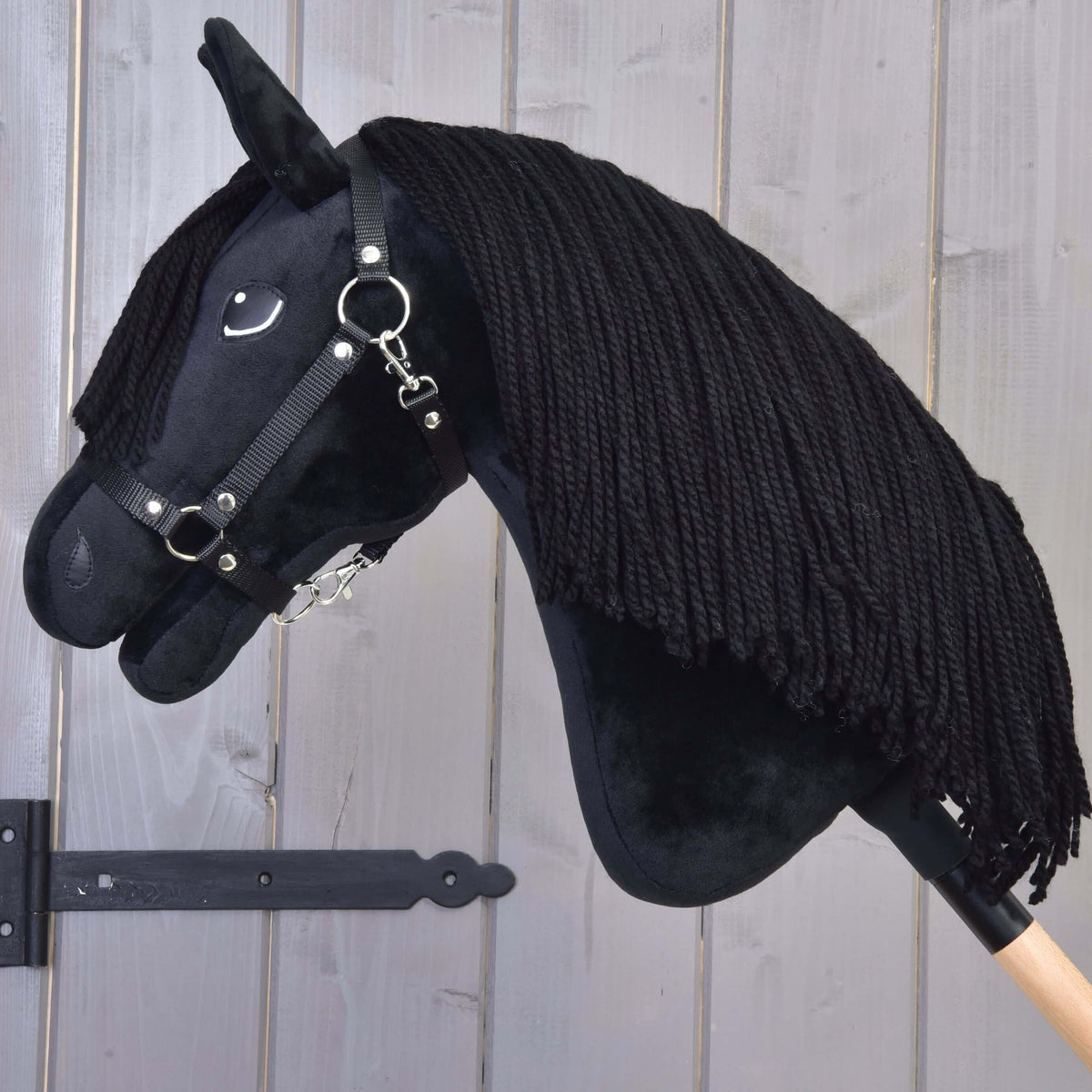 Hobby Horse Mahal with Black Halter with its head lowered, thick black yarn mane falling over the black plush neck