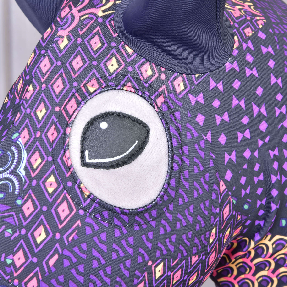 Close-up of the Hobby Horse LarDen Mandala protective suit (Lycra) showing its large embroidered eye and purple fabric with colorful geometric and diamond patterns; a dark ear appears at the top.