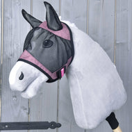The Hobby Horse LarDen Fly Mask De Luxe Pink, a gray plush hobby horse with pink trim and a washable fly mask, is mounted on a wooden stick and set against a wooden plank background.