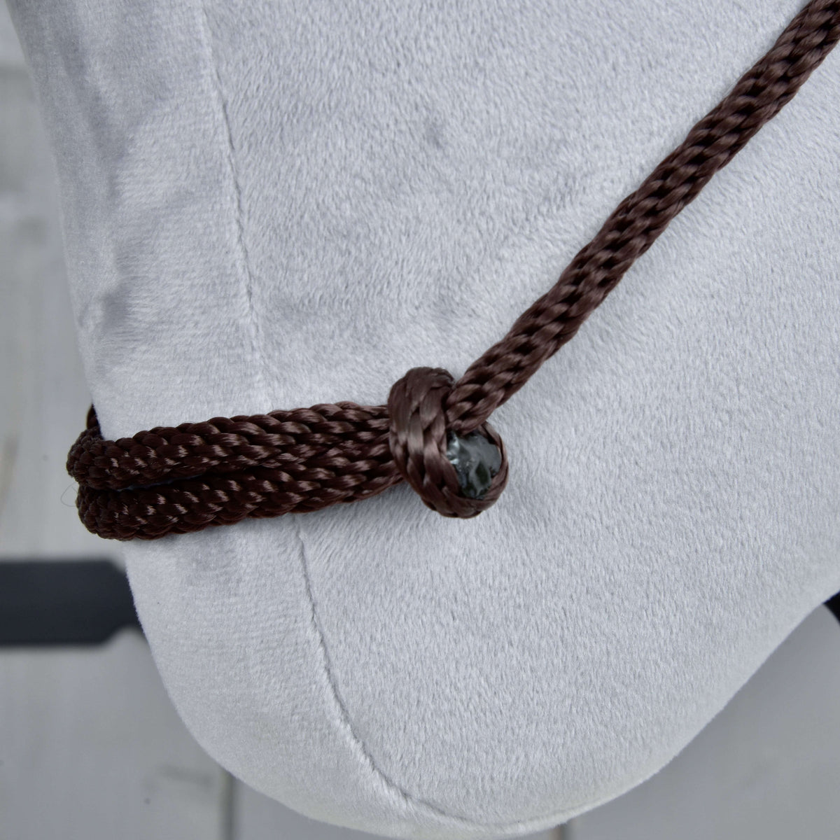 Close-up of the Hobby Horse LarDen Cordeo Chocolate, a brown polypropylene rope tied around the nose of a light gray hobby horse, with detailed views of the knot and rope texture.