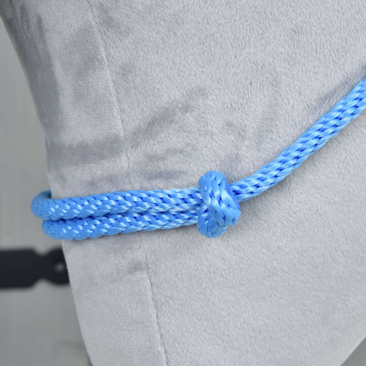 A close-up of the Cordeo Sky by Hobby Horse LarDen—a blue handmade rope tied over light gray fabric and secured with a knot—captures the essence of riding without a bridle.