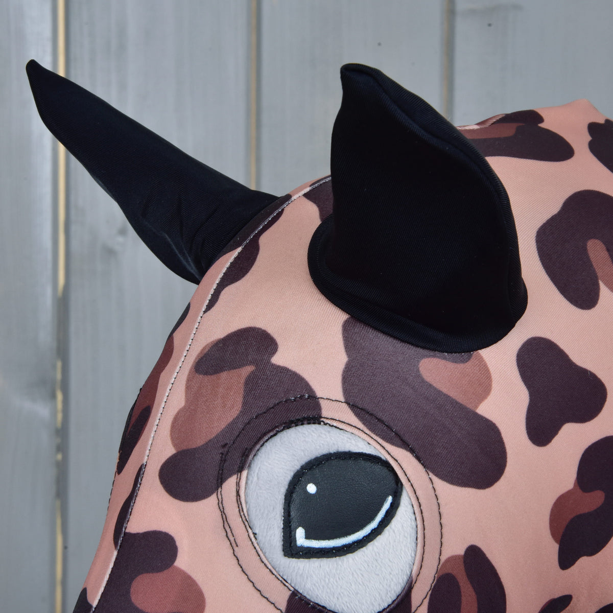 Close-up of the black fabric ears and the eye opening of the leopard print suit on a Hobby Horse head
