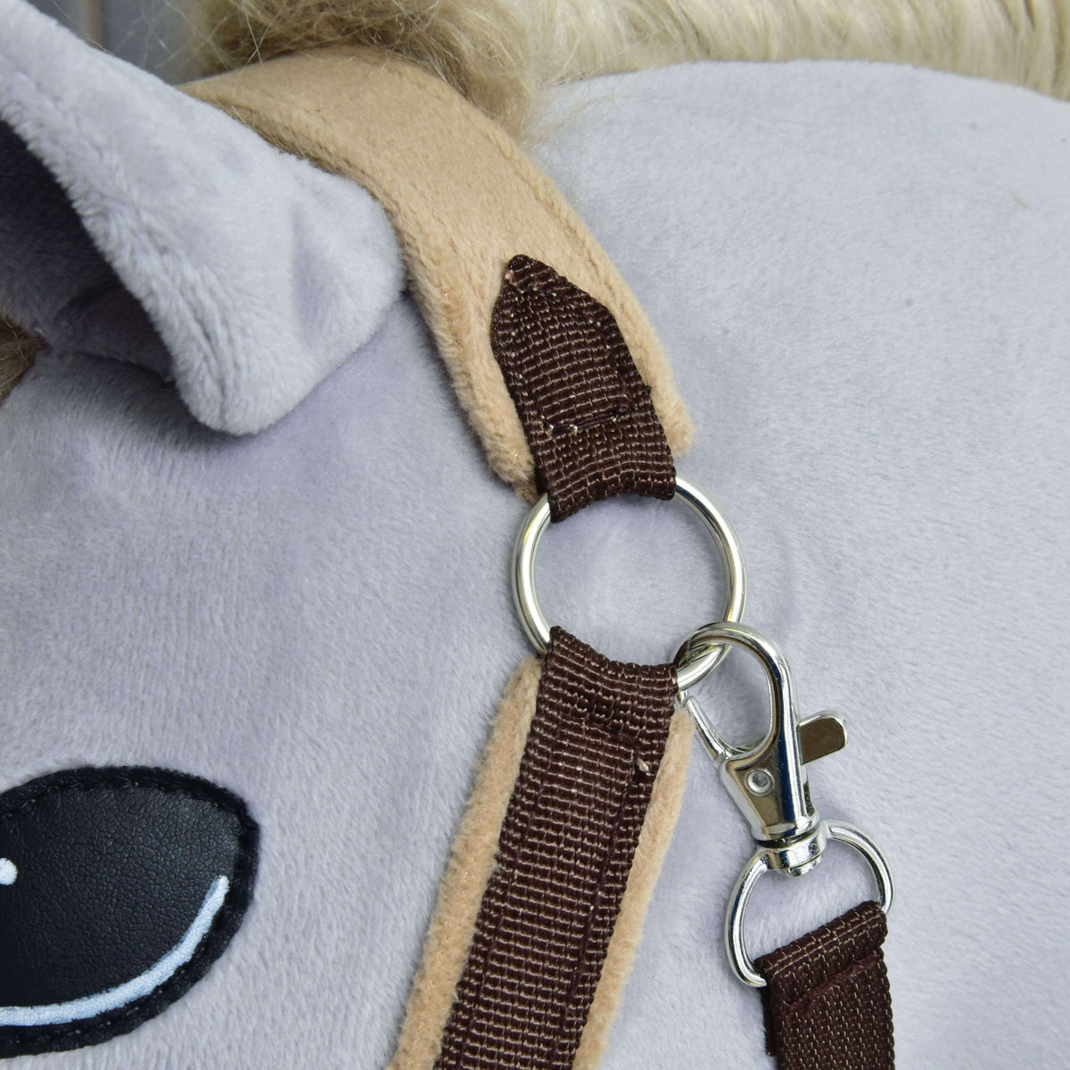 Close-up of the silver ring and snap hook below the ear, where the dark brown strap meets the beige fleece crownpiece
