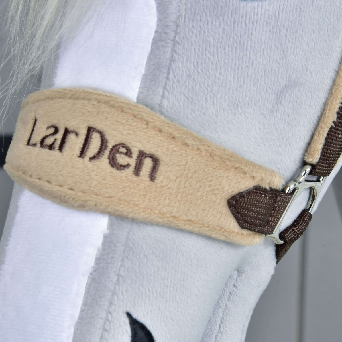 Close-up of the beige fleece noseband with LarDen embroidered in dark brown thread, beside a white blaze