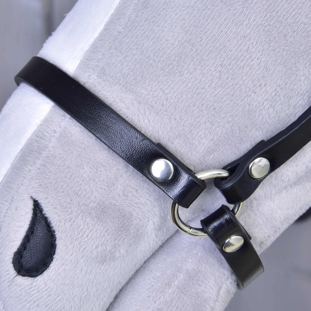 A close-up of a white plush horse toy wearing the Halter - black leatherette by Hobby Horse LarDen, featuring a teardrop-shaped mark under its eye.