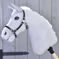 A gray plush hobby horse by Hobby Horse LarDen, featuring a white mane and a Halter - black leatherette, is mounted on a wooden stick against a wooden panel background.